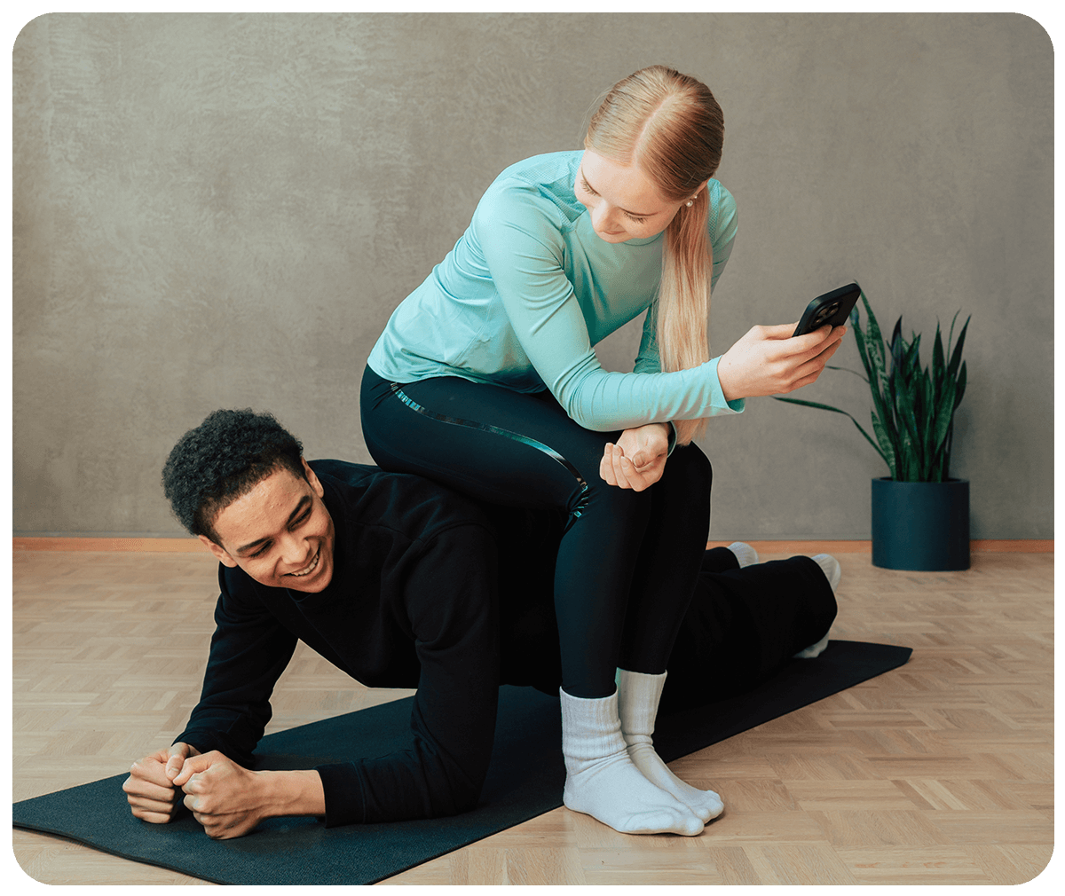 Two young people working out and holding a phone.