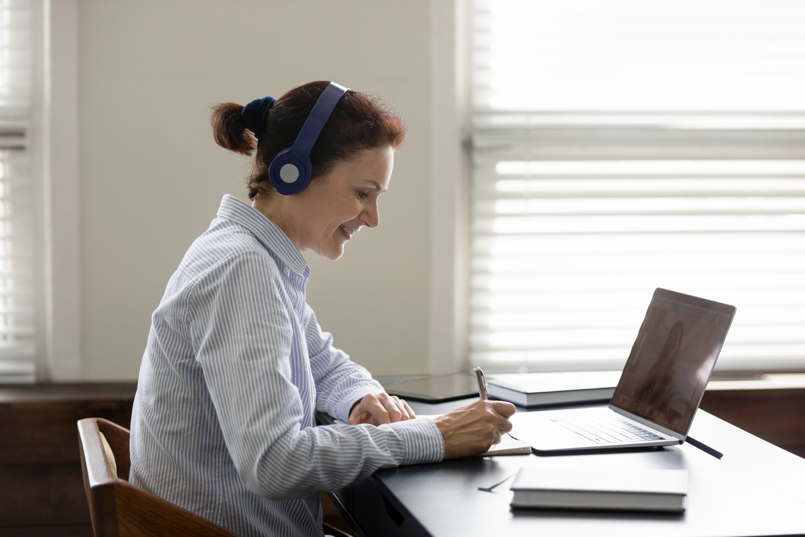 Happy person with headphones on taking a test on a computer.
