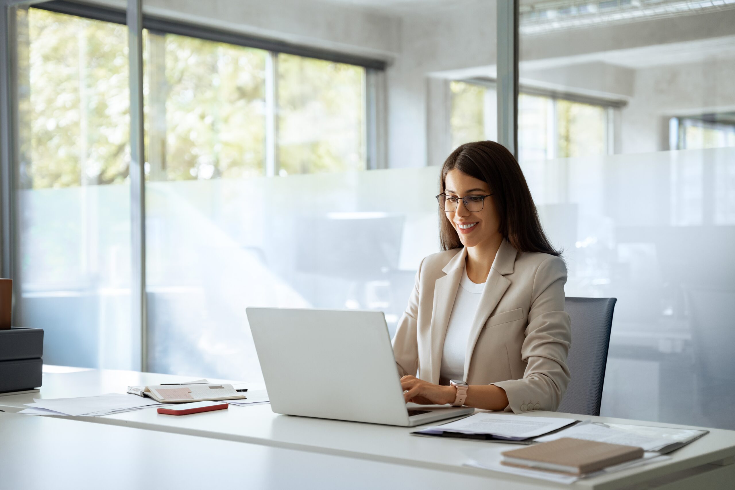 Iloinen nainen tekemässä töitä tietokoneella.